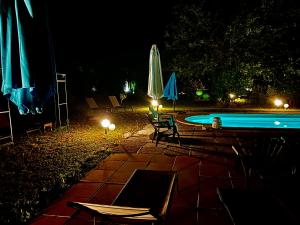 鲁西永Domaine Plan des Devens的游泳池在晚上配有椅子和遮阳伞