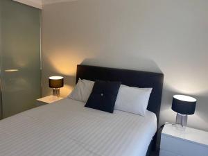 悉尼Ultra Convenient St Leonards Apartment HER09008的一间卧室配有一张带两盏灯的床。