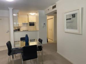 悉尼Ultra Convenient St Leonards Apartment HER09008的一间设有玻璃桌和黑椅子的房间