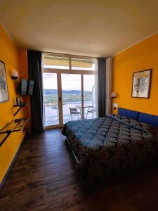 Madonna del SassoHotel Panoramico lago d'Orta的酒店客房设有一张床和一个大窗户