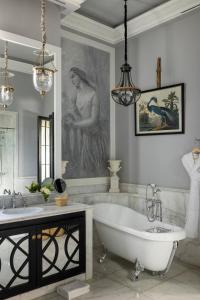 马拉喀什Palais Ronsard Relais & Chateaux的带浴缸的浴室和女人的肖像