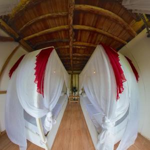 PawenangDe Chicktoria Hostel的卧室配有白色和红色的窗帘和木制天花板