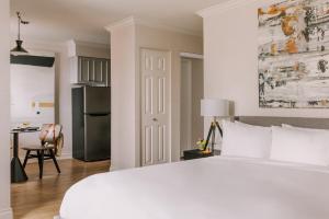 温哥华日落套房酒店的一间白色卧室,配有一张大床和一个厨房