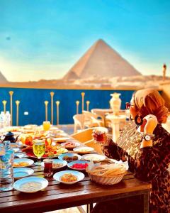 开罗Comfort Sphinx Inn的女人坐在餐桌上吃着食物