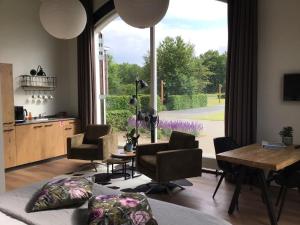 埃尔贝克B&B De Veluwe Hoeve的客厅配有桌椅和大窗户