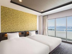 南淡路市Grand Mercure Awaji Island Resort & Spa的酒店客房设有两张床和窗户。