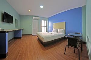信武里府中央公园酒店的一间卧室配有一张床、一张桌子和一张书桌