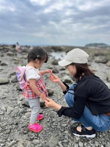 叶山町StellaStoria HAYAMA Seaside house with open-air bath的岩石海滩上的女人和小女孩