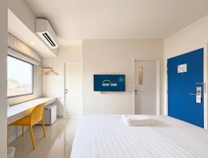 拉差汶里Hop Inn Ratchaburi的一间卧室配有一张床、一张书桌和一个窗户。
