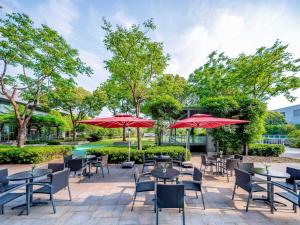 上海上海浦东绿地假日酒店(原上海浦东盛高假日酒店) 的一个带桌椅和红色遮阳伞的庭院
