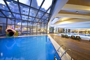 拉瑞Limak Lara Deluxe Hotel & Resort Antalya的一座带大窗户的建筑中的游泳池