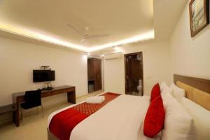 新德里Airport Hotel Peebles的一间卧室配有一张床、一张书桌和一台电视