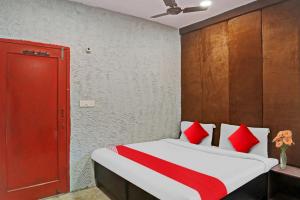 新德里Flagship Kashish Residency的一间卧室配有红色和白色枕头的床