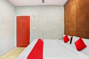 新德里Flagship Kashish Residency的一间卧室设有红色的门和一张带红色枕头的床
