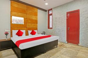 新德里Flagship Kashish Residency的一间卧室设有一张大床和红色的门