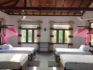 帕西库达Aki Villa的一间设有四张床、粉色床单和窗户的客房