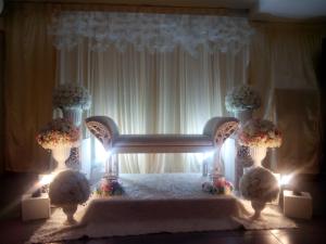 加央斯里花园酒店的一间设有鲜花和灯光的床的客房