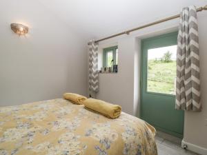 切普斯托Bottom Lodge的一间卧室配有一张带黄色棉被的床和窗户