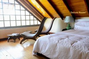 努沃勒埃利耶茶园别墅的一间卧室配有一张床、一把椅子和窗户。