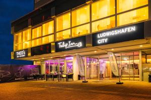 莱茵河畔路德维希港Tulip Inn Ludwigshafen City的一座在晚上有桌子的建筑