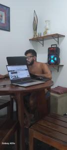 皮帕Pelados Beach Hostel的坐在桌子上的人,手提电脑