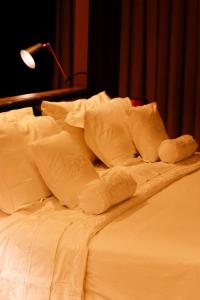 戈亚尼亚QS Marista Hotel的一张带白色床单和枕头的未铺好的床