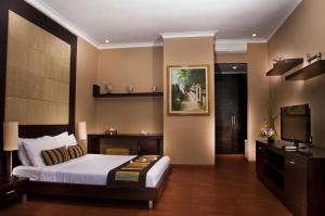 沙努尔信德梅特套房酒店的一间卧室配有一张床和一台平面电视