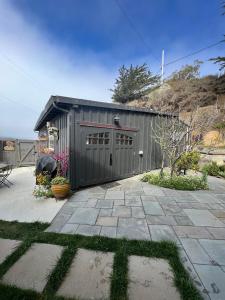 MarshallCarriage House Waterfront On Tomales Bay With Dock的灰色的建筑,设有车库和庭院