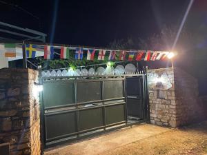 萨兰达Camping Albania-Secret Village Den的夜晚在上面挂有旗帜的绿色大门