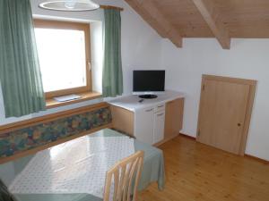 圣坎迪朵Oberpapping的一间设有桌子、电视和窗户的房间