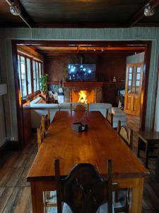 蓬塔阿雷纳斯Alojamiento Punta Arenas的用餐室设有一张大木桌和一个壁炉