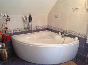 SzypliszkiNoclegi Pod Borkiem的浴室设有大型白色浴缸,铺着瓷砖