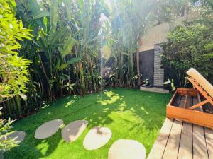 坎古Villa Royal Canggu - 3 minutes to FINNS Beach club!的种有长凳、草和植物的花园