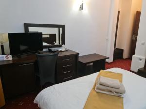 皮特什蒂Hotel Magic GT Trivale的一间卧室配有一张床和一张书桌及电视