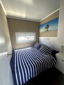 希洪Casa Flotante Gijón的一间卧室配有条纹床和窗户