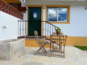 JuncalQuinta dos Avós的门廊上的椅子和桌子,带绿门