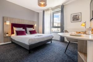 南希Nemea Appart Hotel Grand Cœur Nancy Centre的酒店客房配有一张床铺和一张桌子。