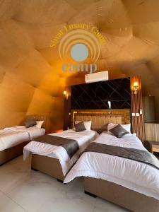 瓦迪拉姆Siwar Luxury Camp的墙上有露营标志的客房内的两张床