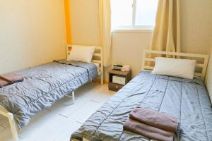 首尔Travelers A Korea Hostel的客房设有两张床和窗户。