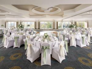 贝德福德Mercure Bedford Centre Hotel的宴会厅配有白色的桌椅和鲜花