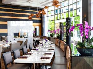 温哥华Fairmont Waterfront的一间设有白色桌子和紫色鲜花的餐厅