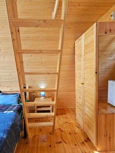 梅斯蒂亚Cozy Cottages的一间设有木墙、一张床和梯子的房间