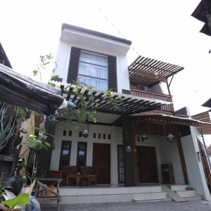 TimuranINEZ Homestay Prawirotaman Yogya的白色的房子,设有窗户和桌子