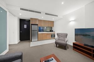墨尔本Flinders Street Apartments的客厅配有椅子和电视