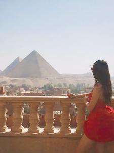 开罗Crowne Pyramids view inn的坐在金字塔的树 ⁇ 上的女人