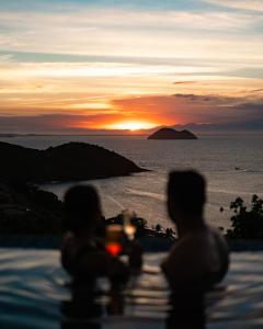 布希奥斯Buzios Mar Hotel & Spa的两人坐在游泳池边,欣赏日落