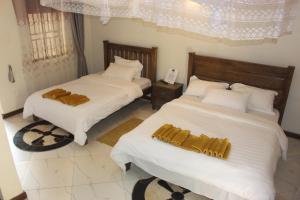 波特尔堡Montane Safaris Hotel的一间卧室配有两张带白色床单和金色枕头的床。