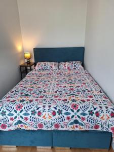 什切青Turkusowa Apartament的一张带花卉床罩的蓝色床架床
