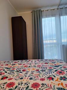 什切青Turkusowa Apartament的一间卧室配有一张带花卉床罩的床和窗户。