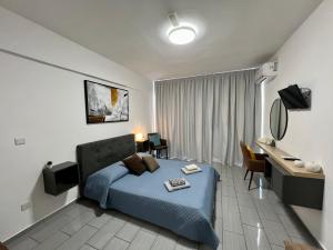 LivadhiaFatCow Seaside Suites的一间卧室配有蓝色的床、一张桌子和椅子